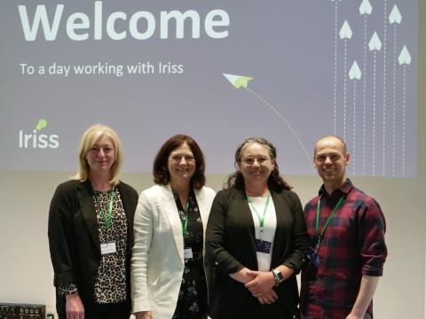 4 people stand in front of a projected screen saying welcome