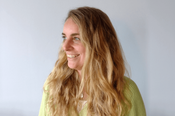 a headshot of a lady in green jumper smiling looking off to the left