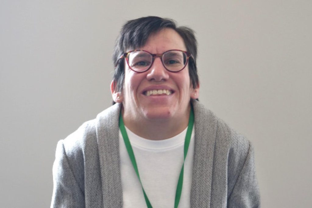 Catherine Garrod smiling, wearing glasses and a green lanyard