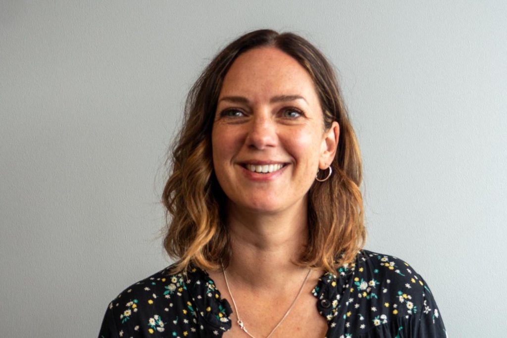 Ellen Daly smiling in a dark floral top