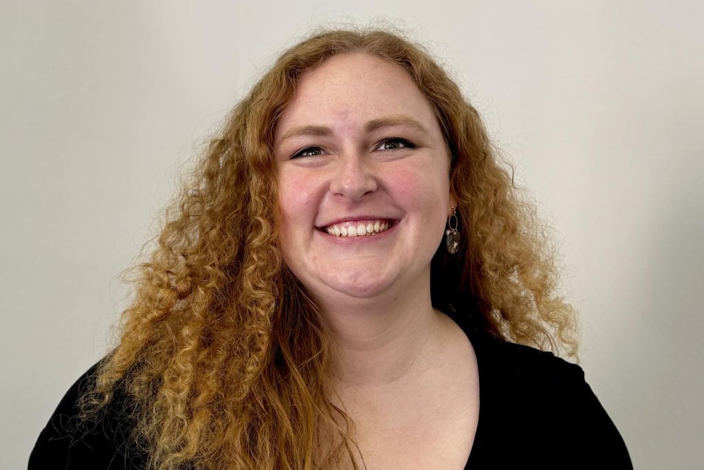 Katie Feyerabend smiling, with long curly red hair