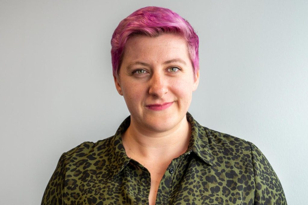 Sam Ella with short pink hair, in a leopard-print shirt